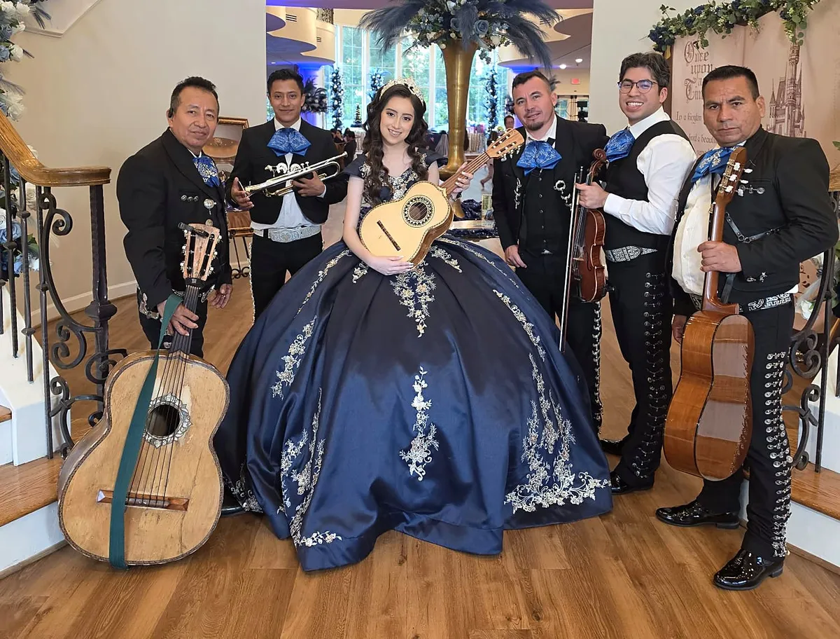 El mariachi acompañando a una quinceañera con vestido azul en un salón de Houston