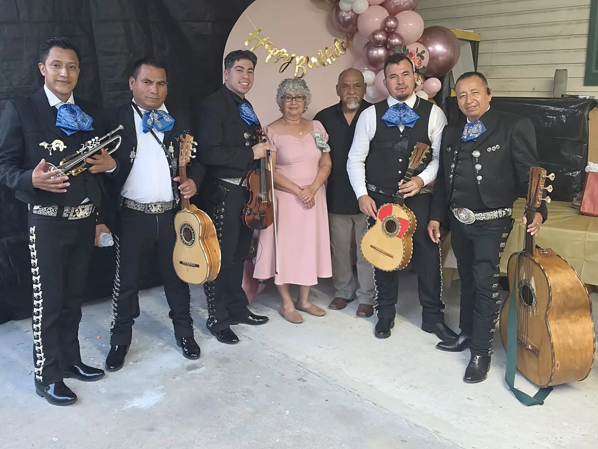 El grupo con la festejada y su familia ante un arco de globos rosados de cumpleaños