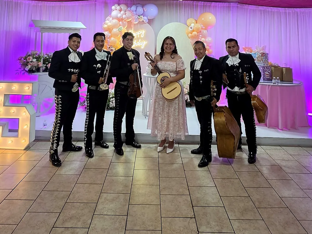 El mariachi con la quinceañera en un salón iluminado de morado